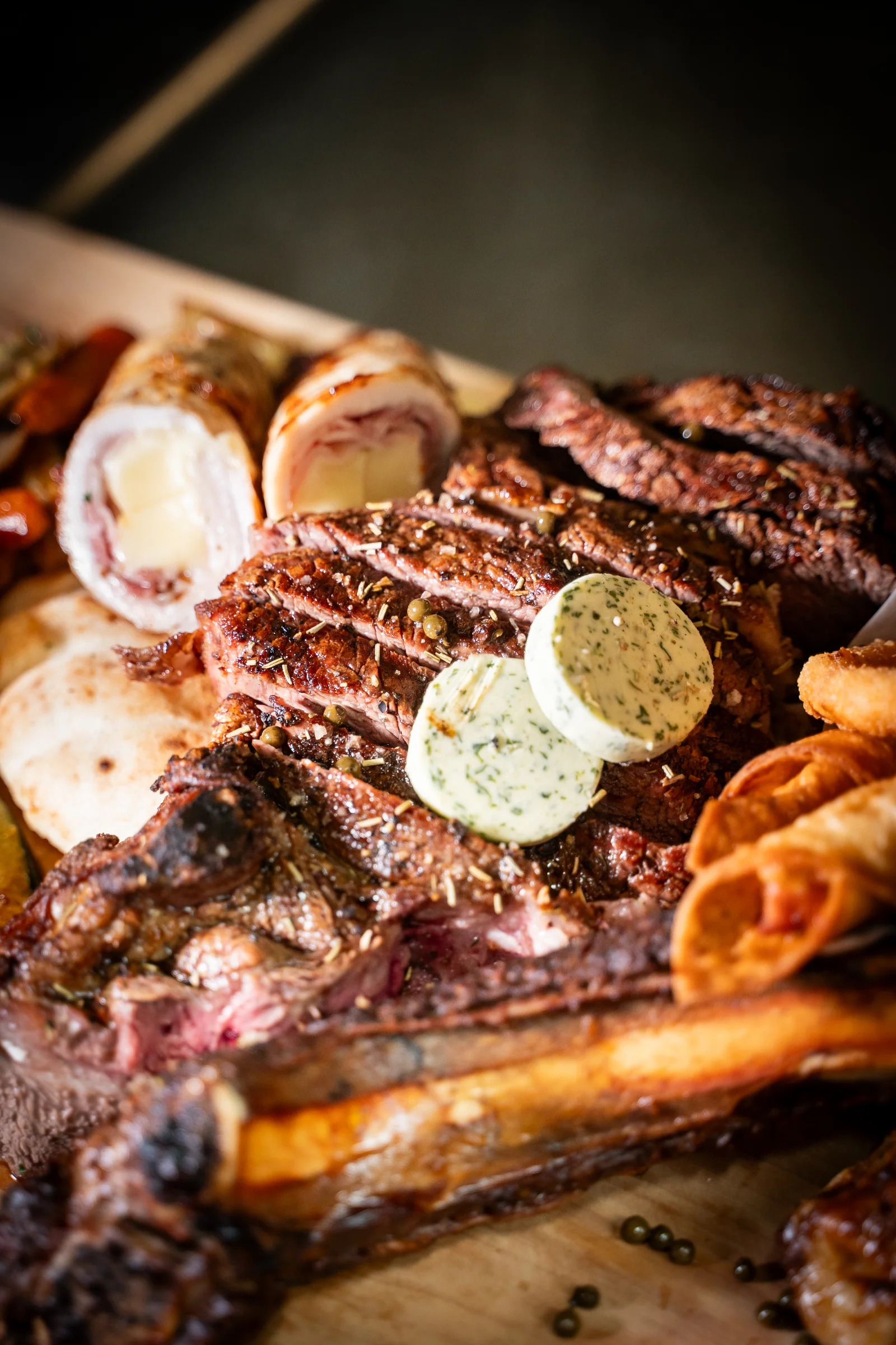 Narezan steak z zeliščnim maslom na leseni plošči